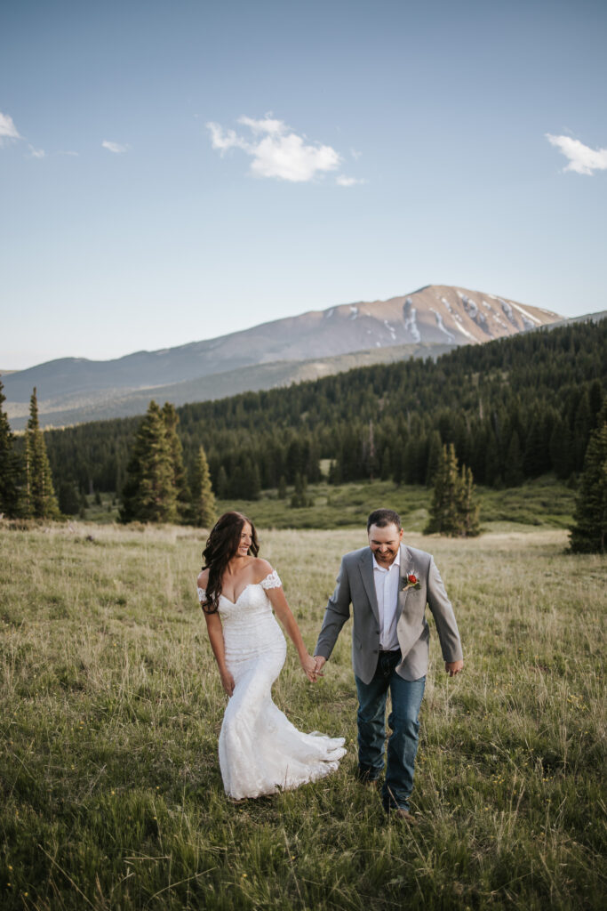 Couple walking and holding hand on their Breckenridge elopement day while they smile at each other beautifully.