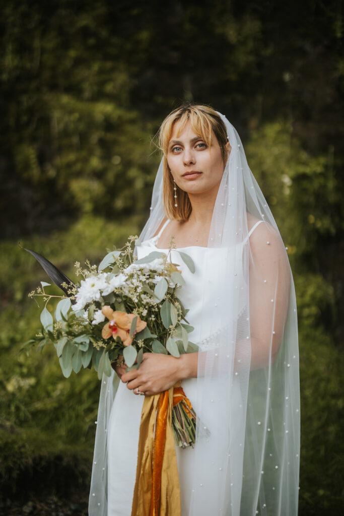 Bride smiling softly at the camera with a beautiful green moss background from Iceland.