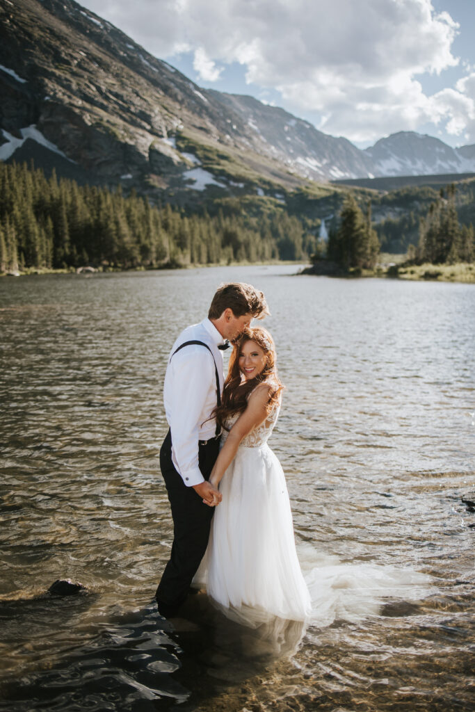 Couple hugging each other in a lake in the mountains on their Breckenridge elopement day.
