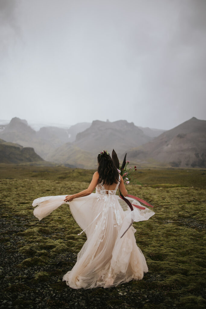 Bride twirling around in her dress in the rain on her elopement day in Iceland.