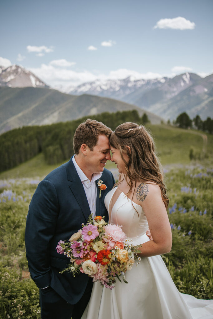 Beautiful mountain couple eloping among the wildflowers with a couple who is hugging each other and smiling really big.