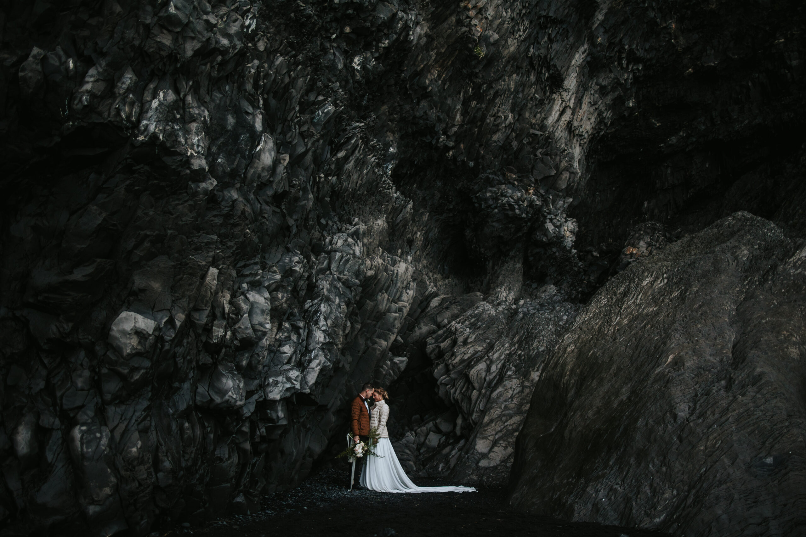 Couple taking a moment alone together on the black sand beaches of their Icelandic elopement.