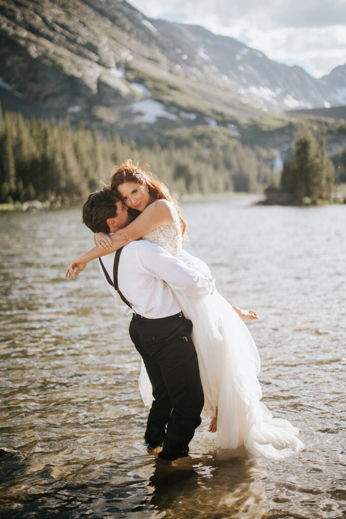 Couple standing in the water of an alpine lake in their wedding clothes for their Breckenridge, Colorado elopement.