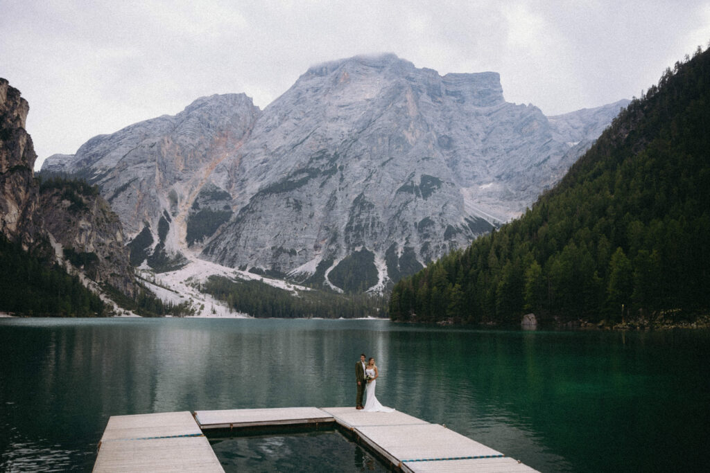 Couple standing on a dock on the lake for their Italy elopement at Lago Di Braies.