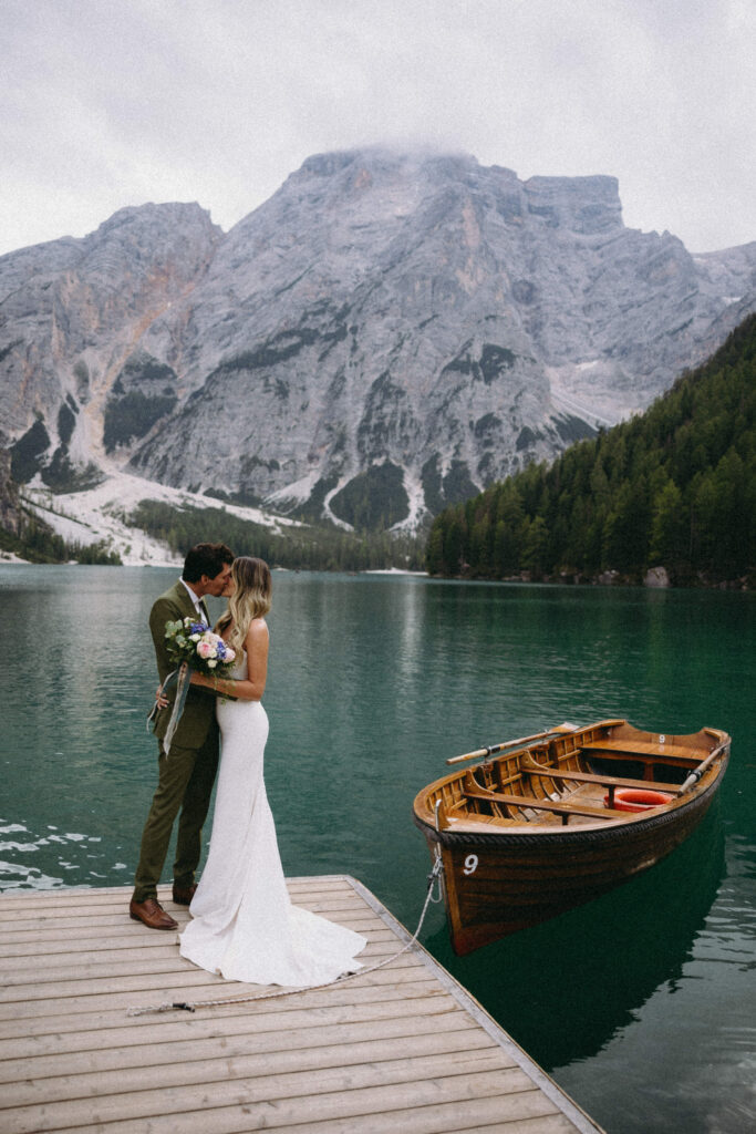 Couple standing on a dock for their Italian elopement at Lago Di Braies.