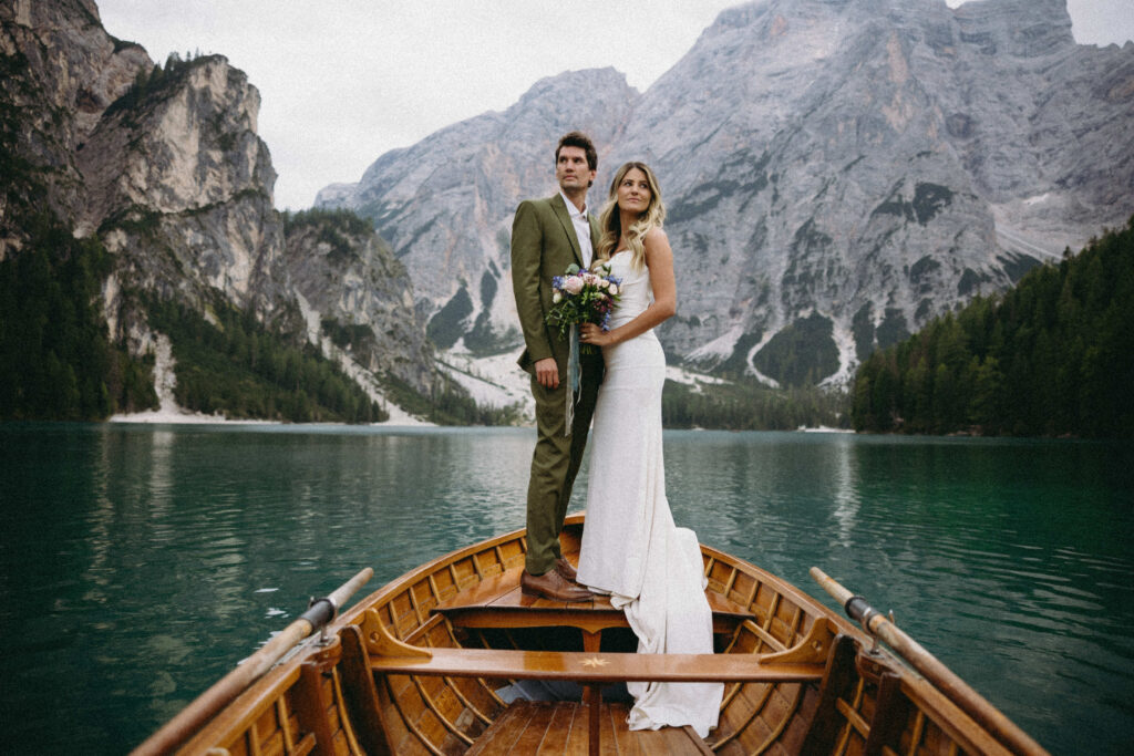 Couple standing on a boat for their Italy elopement at Lago Di Braies.