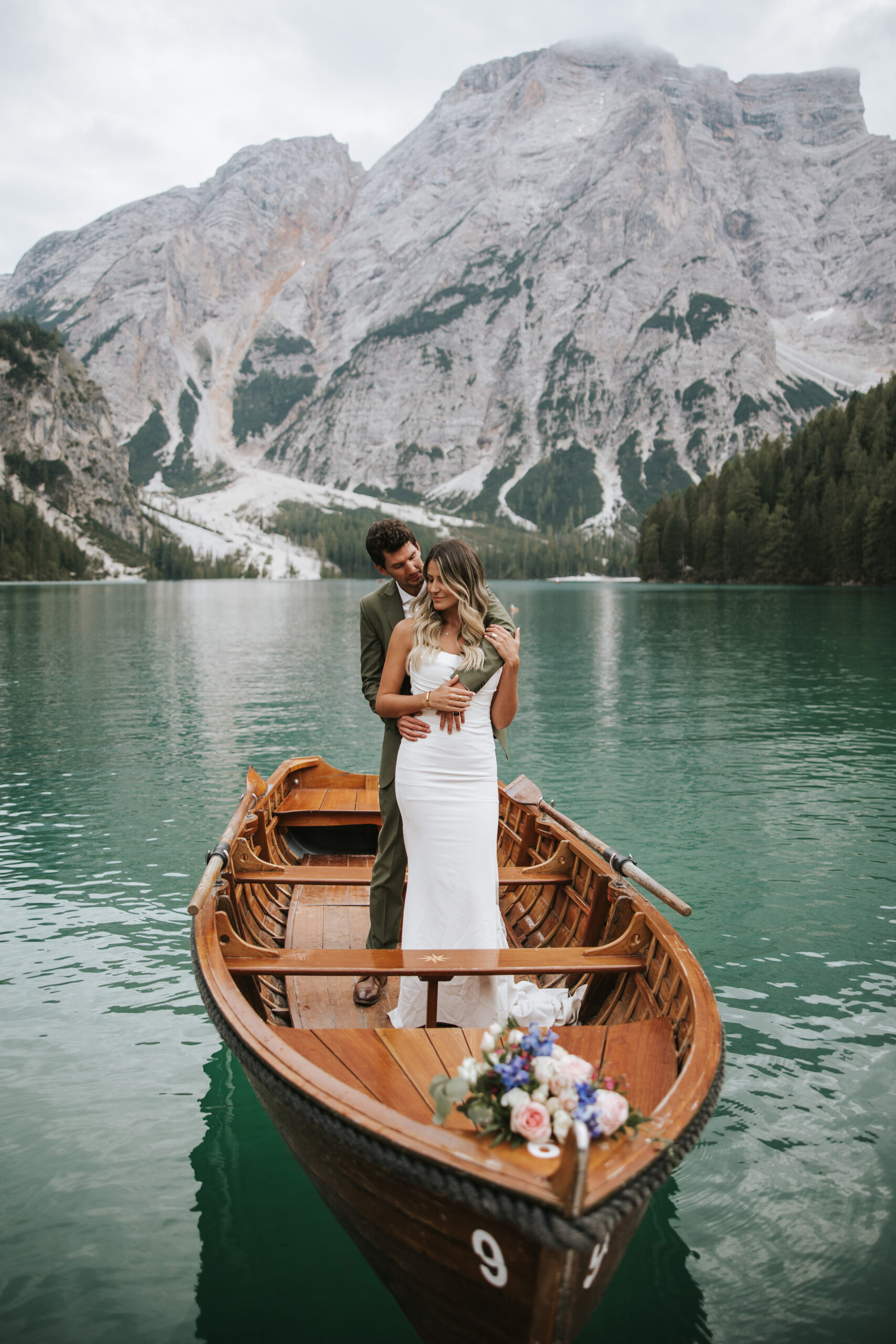 Couple standing on a boat for their elopement at Lago Di Braies.